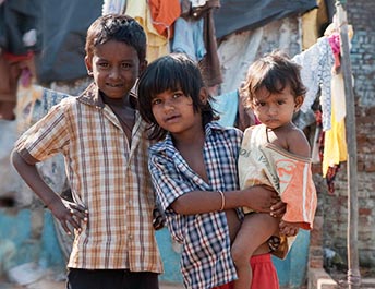Two young children standing together outside their home